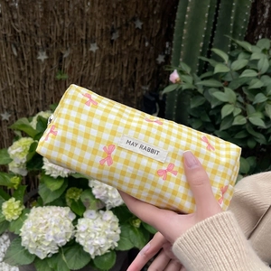 Detail of yellow checkered makeup bag with pink bow prints and brand label
