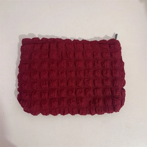 Close-up of deep wine red popcorn fabric cosmetic bag with black zipper closure