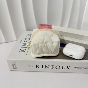 Close-up of white quilted storage pouch with pearl zipper and pink rabbit label