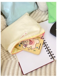 Close-up of cream cosmetic pouch with yellow zipper and red hi jolly embroidered label