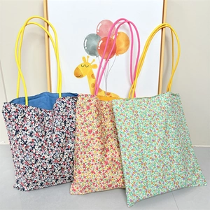 Detailed view of floral canvas tote bags in navy blue, yellow, and green floral patterns