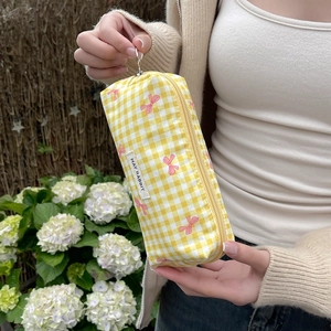 Detail of yellow checkered makeup bag with pink bow pattern and side fabric label