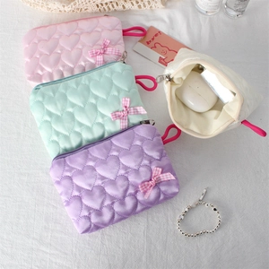 Detailed view of quilted heart pouch storing wireless earbuds in soft macaron colors
