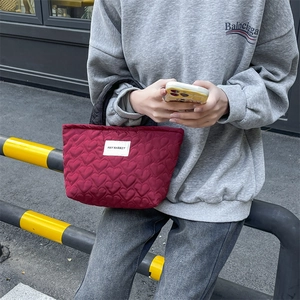 Macro shot of burgundy quilted heart pattern handbag with brand label in street setting