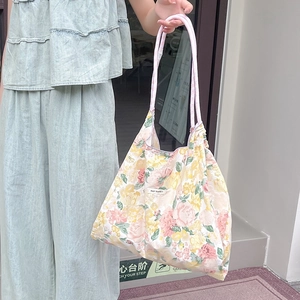 Borsa tote in tela floreale con spalline rosa ed etichetta portata da una modella