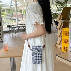 Detail of gingham mini phone bag featuring a soft rope strap and woven brown accents