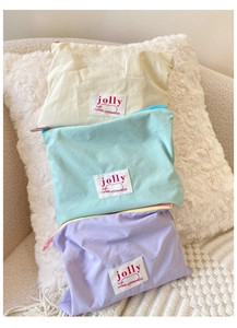 Detailed shot of pastel zipper pouches in yellow, mint, and purple on soft plush fabric