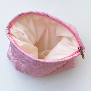 Close-up of pink heart-quilted makeup bag showing spacious cream lining and metal zipper