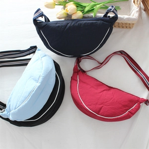 Nylon crescent crossbody bag in four colors with adjustable striped strap on a bright background