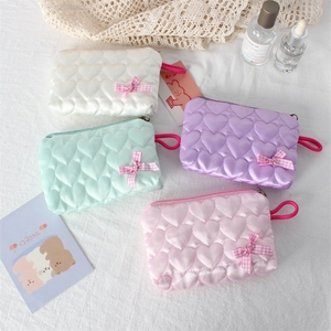 Detail of heart-quilted zipper makeup bags with gingham bows in four pastel colors