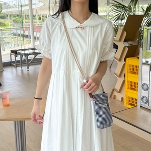Close-up of white Peter Pan collar dress with embroidery and checkered crossbody bag