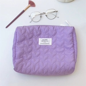 Detail view of purple quilted makeup bag with heart stitching and top zipper closure