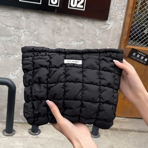Close-up of quilted black toiletry bag with puffer texture and woven brand label