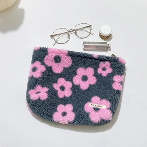 Close-up of floral plush makeup bag with pink flowers and branded woven label detail