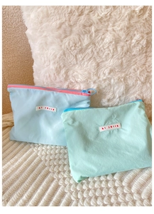 Close-up of pastel macaron cosmetic bags in light blue and mint green with hi jolly logo