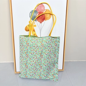 Close-up of floral canvas tote bag showing colorful flower print and yellow straps