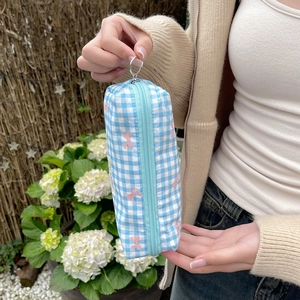 Close-up of blue checkered pouch with pink bow embroidery and silver metal zipper ring