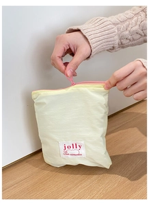 Gros plan d'une trousse à maquillage jaune avec fermeture éclair rose et étiquette