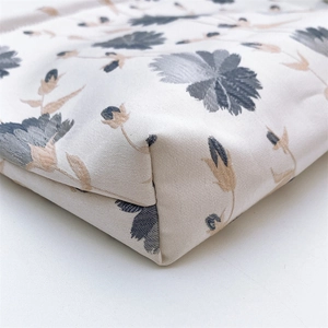 Detailed view of the stitched corner and floral print on a canvas cosmetic bag