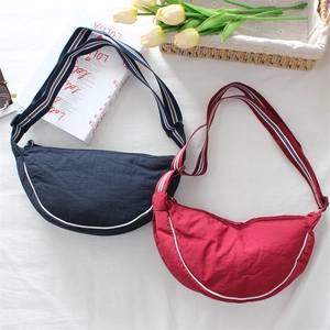 Detail of navy blue and burgundy dumpling bags with white piping and striped straps