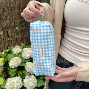 Detail of blue plaid cosmetic bag with pink bow pattern and May Rabbit woven label