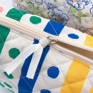 Detailed close-up of quilted floral cosmetic bag with zip and ribbon puller detail
