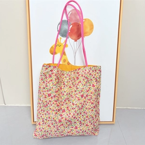 Detailed shot of floral canvas tote bag with pink rope handles and yellow inner lining