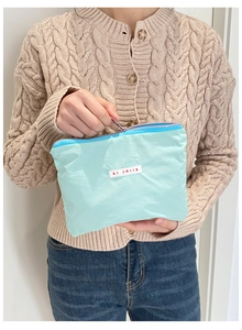 Close-up of a mint green fabric pouch with zipper closure and white logo tag for storage