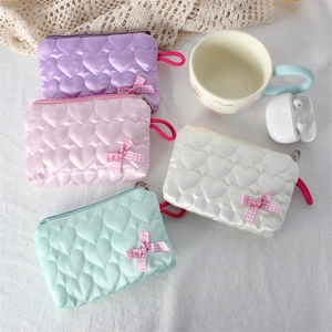 Detailed view of four colorful heart-quilted satin pouches with plaid bows and zippers