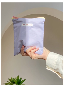 Gros plan d'une trousse à maquillage lilas en nylon avec fermetures éclair colorées
