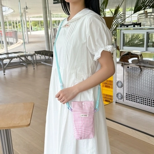 Detail of pink plaid fabric phone bag featuring May Rabbit label and woven strap