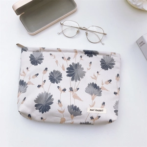 Detailed close-up of floral jacquard makeup bag with zipper and branded label