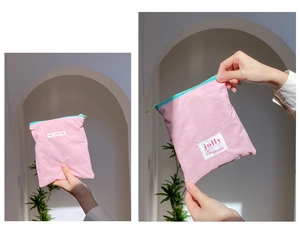Détail d'une pochette rose en nylon avec étiquette tissée blanche et tirette zippée