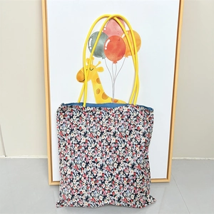Detail of floral pattern tote bag with yellow handles and navy blue inner lining