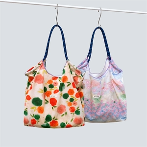 Dettaglio di borse tote in tela a fiori con manici in corda blu scuro appese in mostra