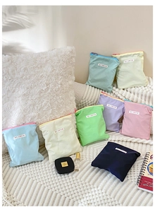 Vue à plat de trousses à maquillage colorées en tissu pastel sur texture douce