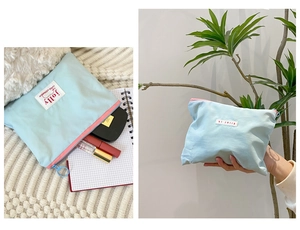 Macro view of mint green cosmetic bag with blue puller and hi jolly woven label detail