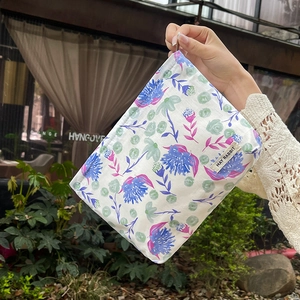 Close-up detail of the vintage floral print on a portable cosmetic storage bag held outdoors