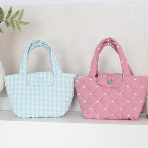Detail of quilted hand bags with blue grid and pink heart patterns with button closure