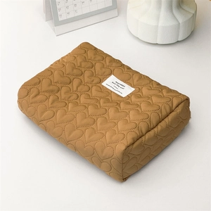 Macro detail of brown quilted heart patterns on a soft fabric cosmetic storage bag
