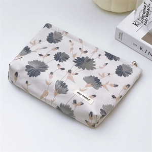Close-up of floral jacquard makeup bag with May Rabbit label on a minimalist desk