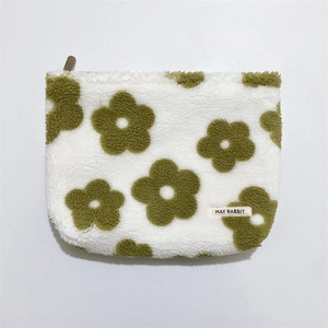 Detailed macro view of soft sherpa fleece texture and green flower pattern on the cosmetic bag