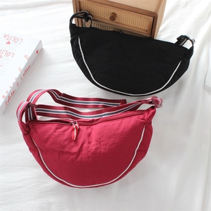 Canvas crescent bags in black and red featuring striped straps and contrast piping