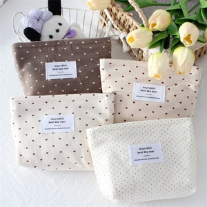 Close-up of four canvas makeup pouches with heart and polka dot patterns and zipper