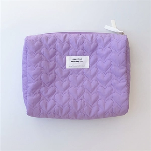 Macro detail of lavender quilted heart pattern and fabric brand label on makeup bag