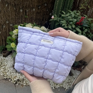 Detail of light purple quilted toiletry bag with soft textured bubbles and brand tag