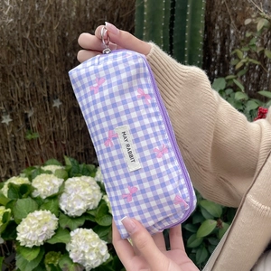 Close-up of purple gingham pouch with pink bow prints and May Rabbit woven label