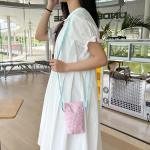 Detailed side view of pink checkered phone bag with adjustable blue rope strap