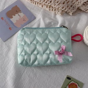 Detail of mint green heart-quilted pouch with a pink checkered bow and red loop