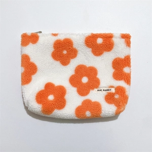 Detail of soft fleece makeup bag with orange flower patterns and zipper closure